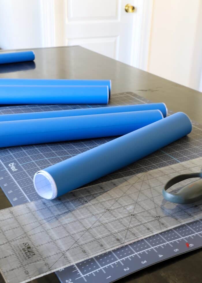 Rolls of solid blue wallpaper on a cutting mat