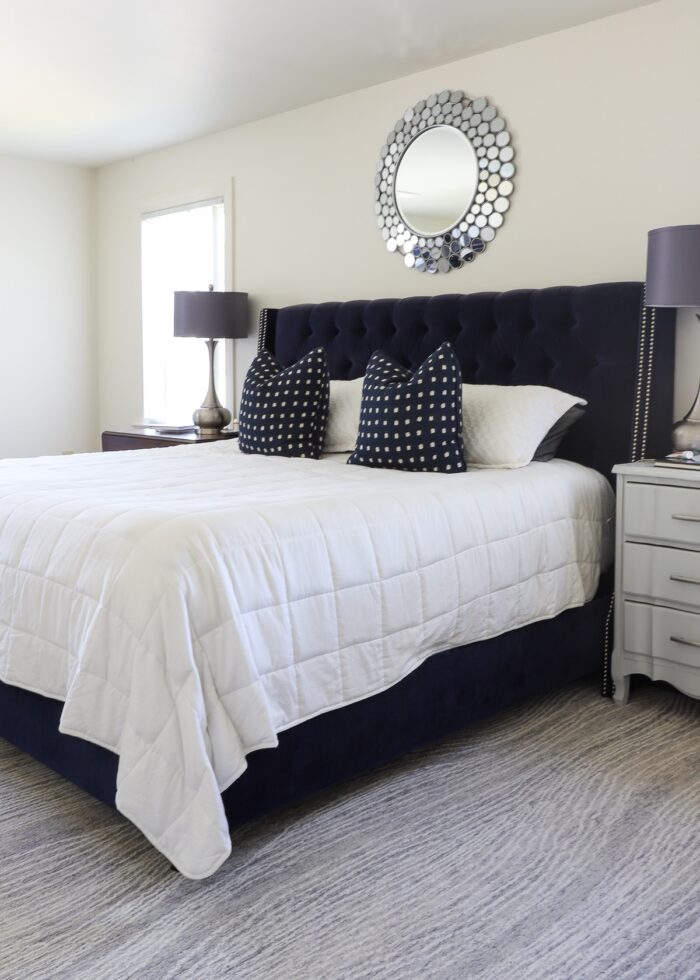 Navy blue bed on a grey carpet against a beige wall
