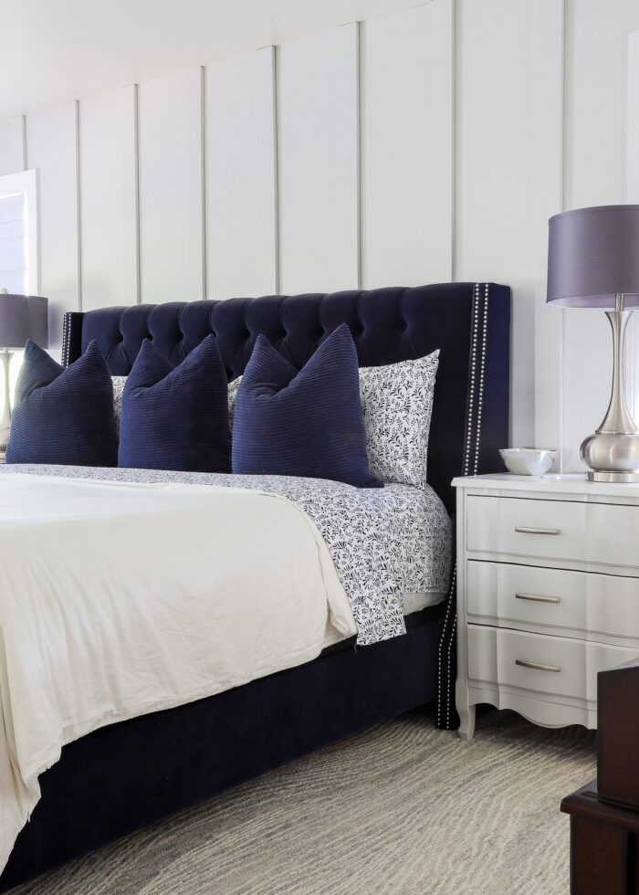 Navy blue bed on a grey carpet against a grey board and batten accent wall