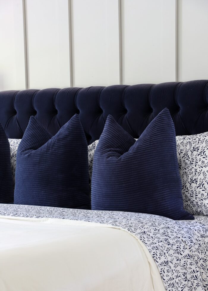 Navy blue bed with blue and white flowered bedding against a grey board and batten accent wall