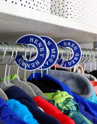 White plastic closet dividers with blue vinyl labels hung on a coat closet rod