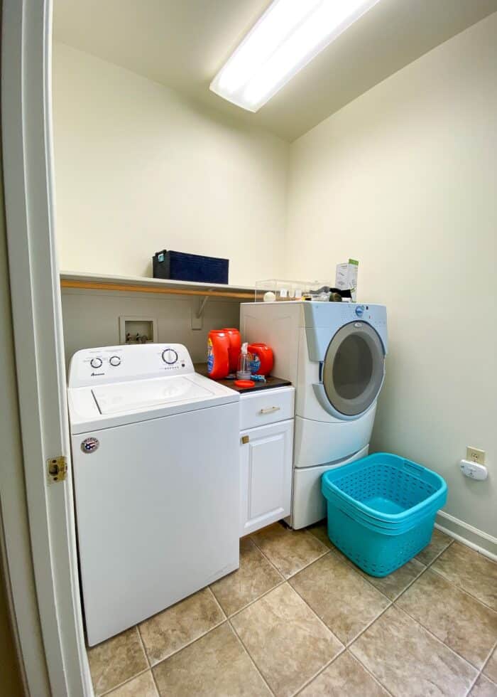 Messy and cluttered laundry room with mis-matched washer and dryer