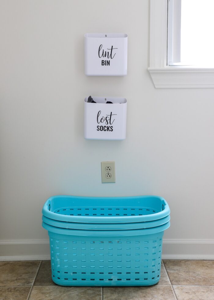 Turquoise laundry baskets underneath two wall-mounted white bins