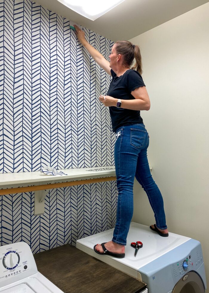 Megan hanging wallpaper in a laundry room