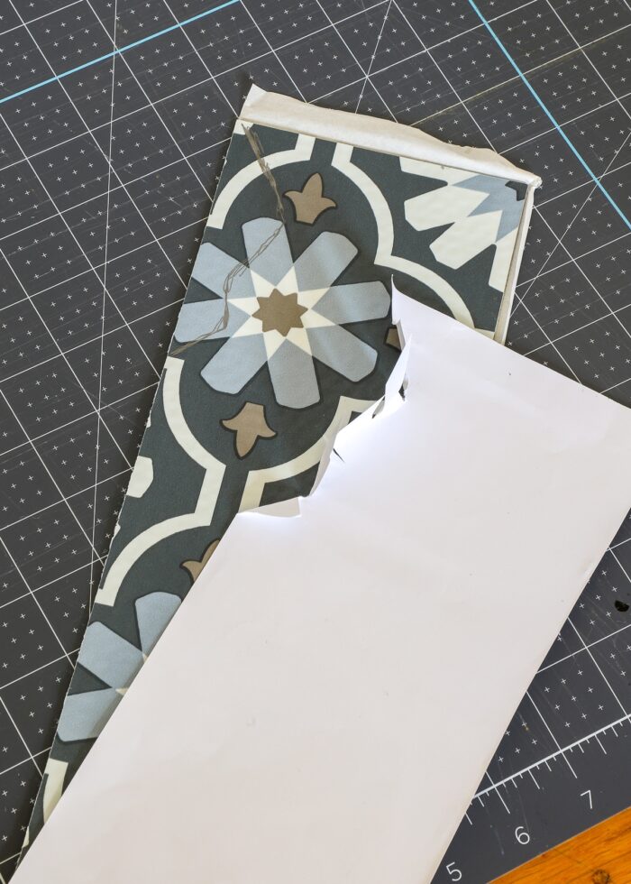 Using paper template to cut peel and stick floor tile for fireplace surround