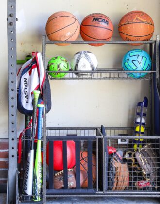 Sports equipment storage rack in a garage loaded up with basketballs, soccer balls, baseball equipment, and more!
