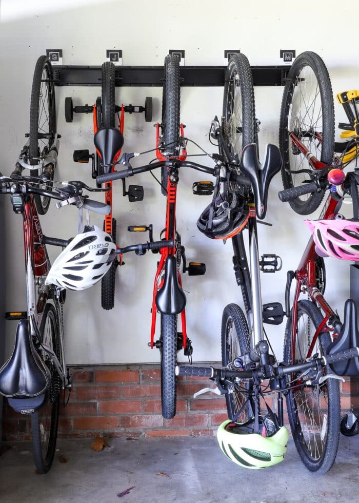 5 bikes mounted to garage wall via a black rail with hooks