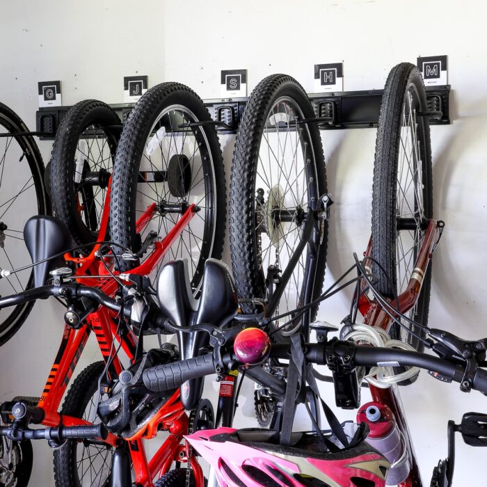 Bikes mounted to garage wall via a black rail with hooks and monogram labels