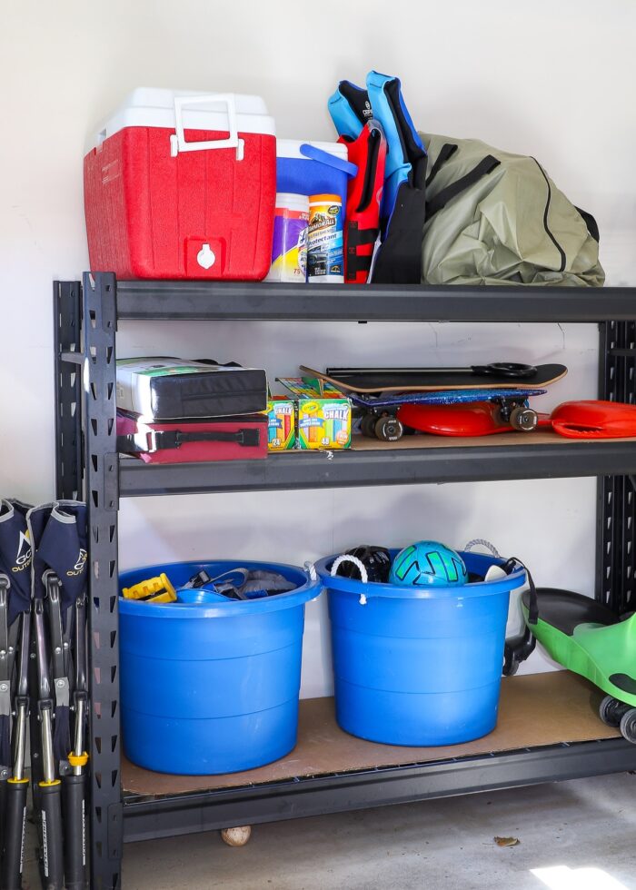 Tubs of sports equipment on garage shelves