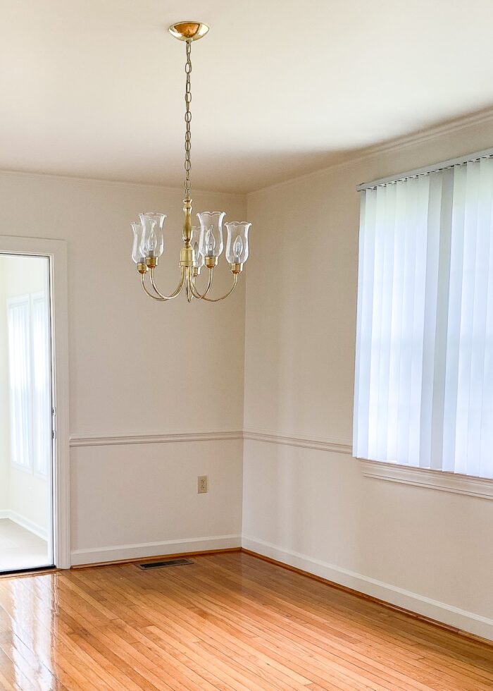 Empty rental dining room with dated brass chandelier