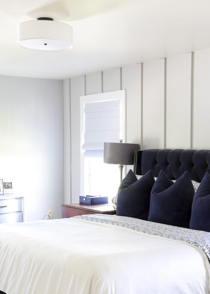 Grey, navy, and white rental master bedroom with classic white flush-mount shade light fixture