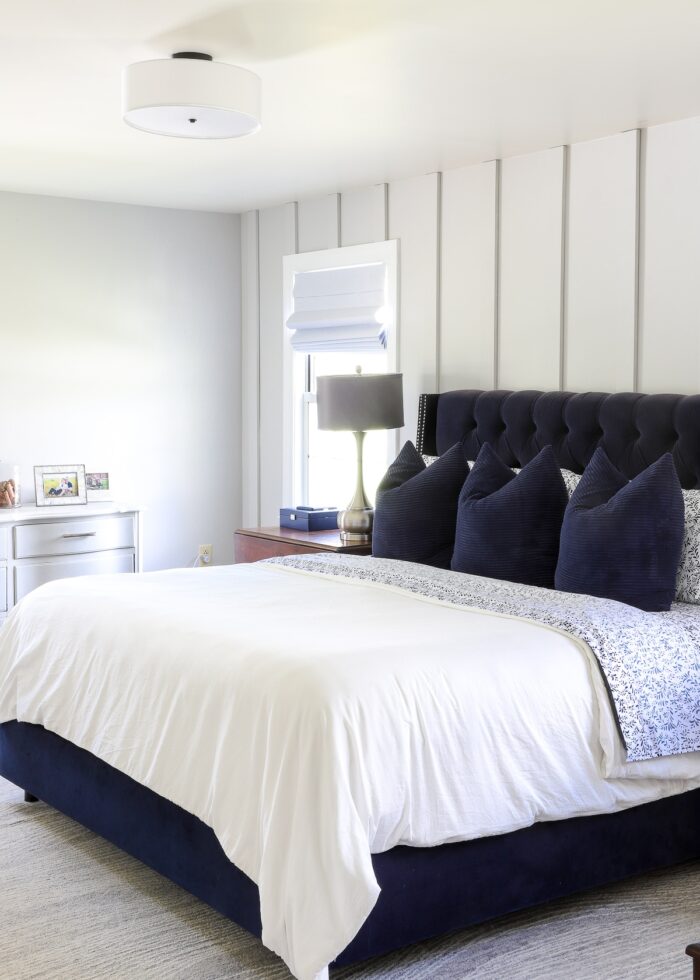 Grey, navy, and white rental master bedroom with classic white flush-mount shade light fixture
