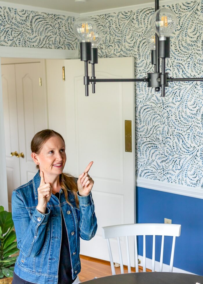 Megan from The Homes I Have Made pointing to a matte black chandelier