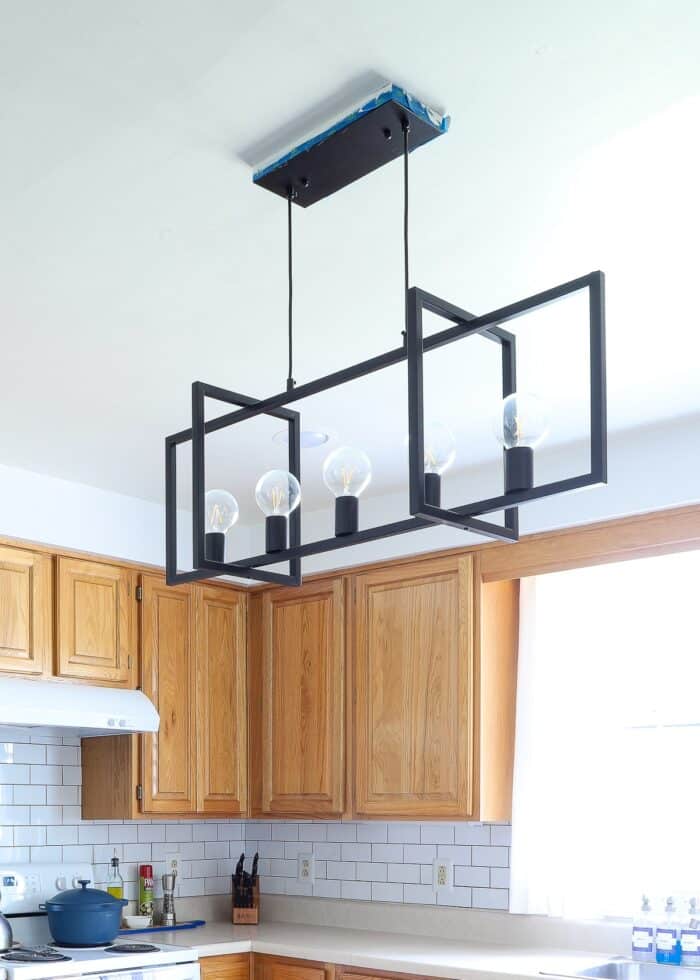 Modern black kitchen island light fixture in rental kitchen with patched and painted ceiling