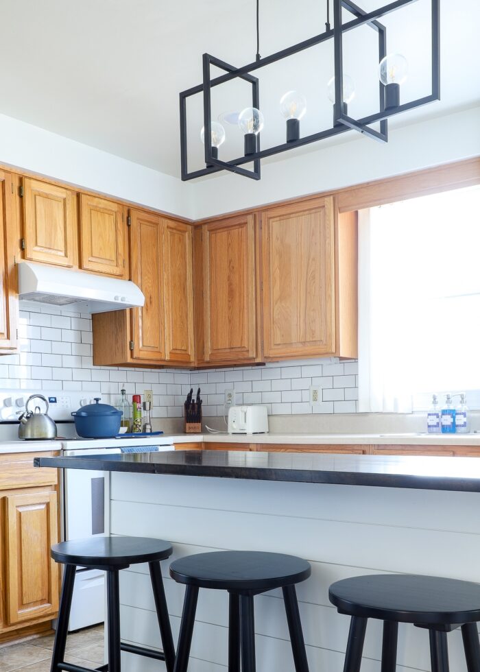 Builder-grade rental kitchen with modern black kitchen island light fixture