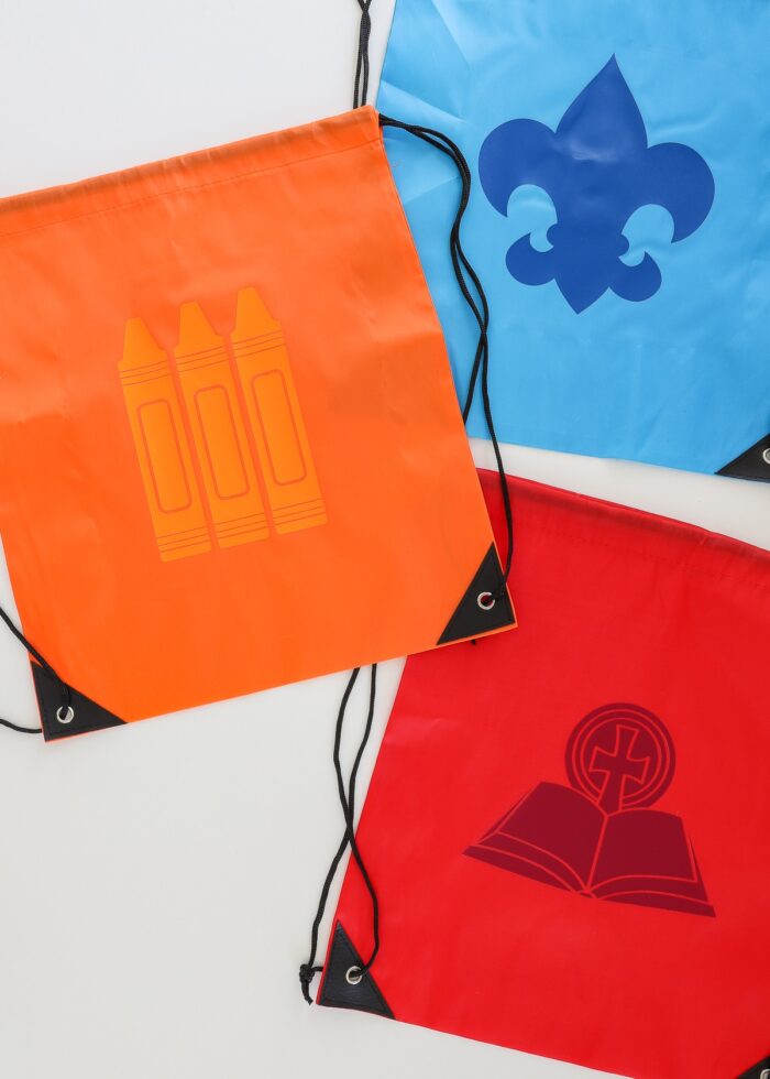 Blue, red, and orange drawstring backpacks with activity icons ironed onto each one