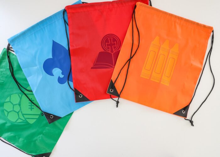 Blue, red, green, and orange custom drawstring backpacks with activity icons ironed onto each one