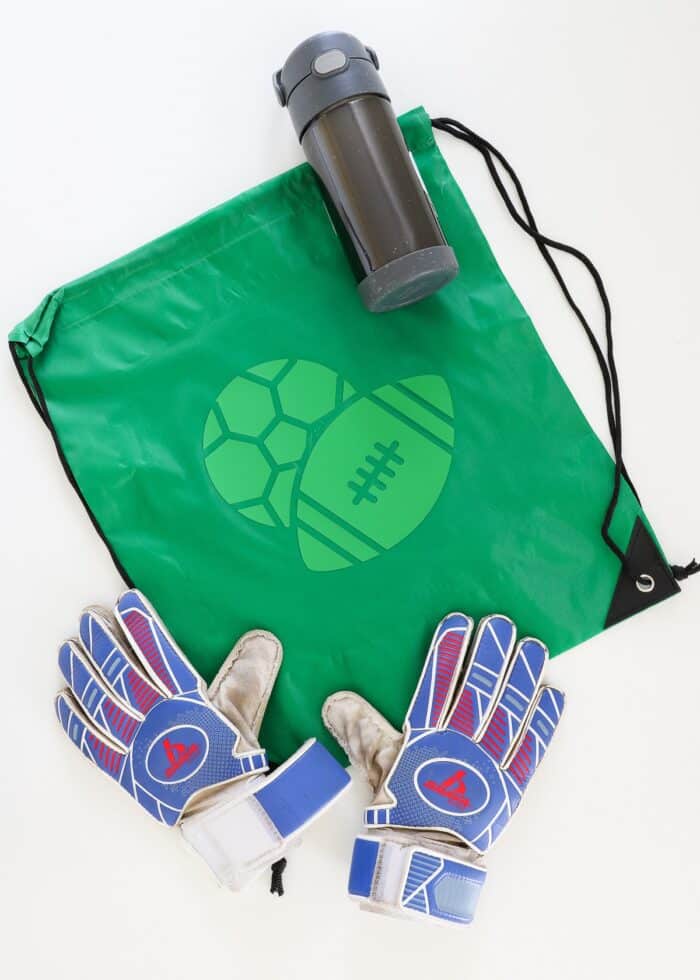 Green sports drawstring backpack shown with goalie gloves and a water bottle
