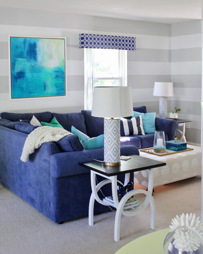 Blue upholstered cornice box above a blue couch on a grey striped wall