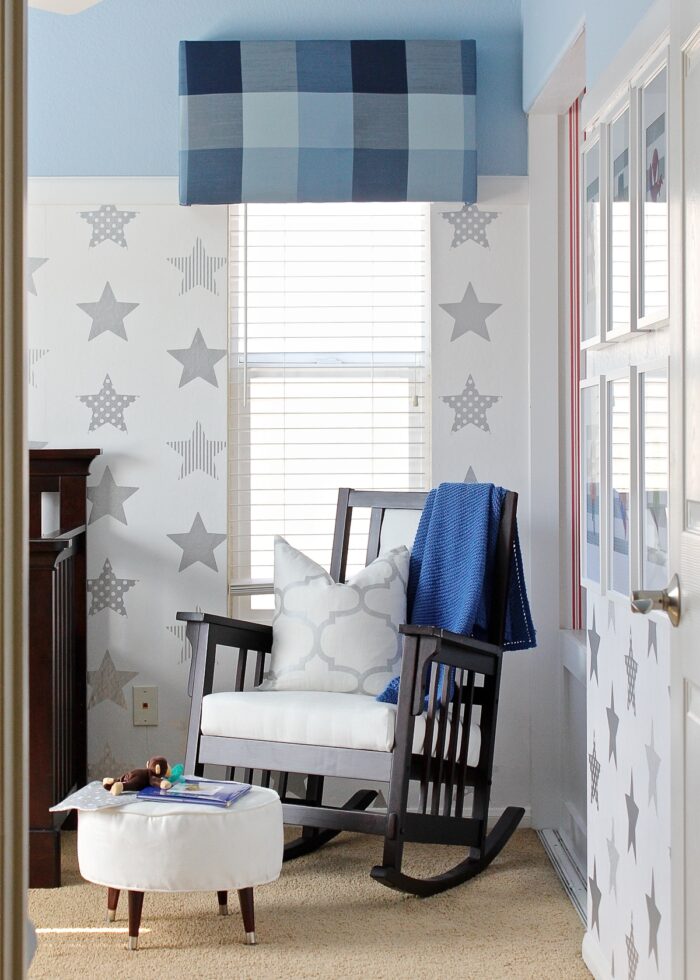 Blue plaid window valance above a rocking chair in a blue and white baby nursery