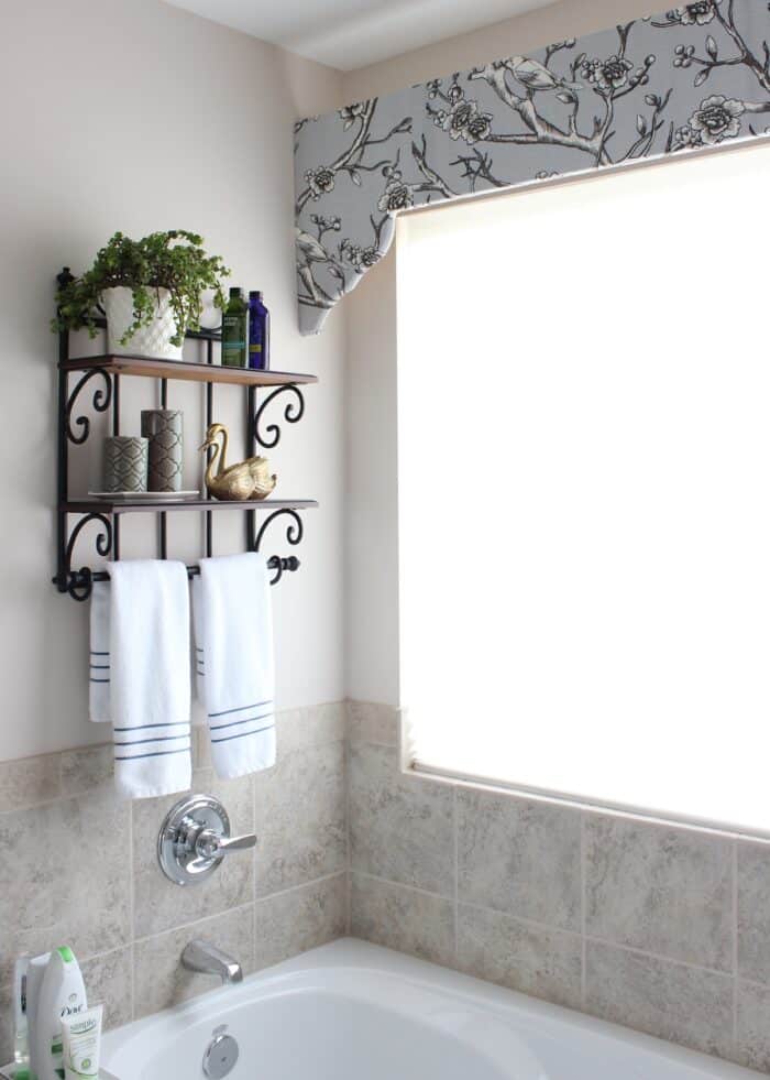 Grey flowered curved window cornice box above a bath tub