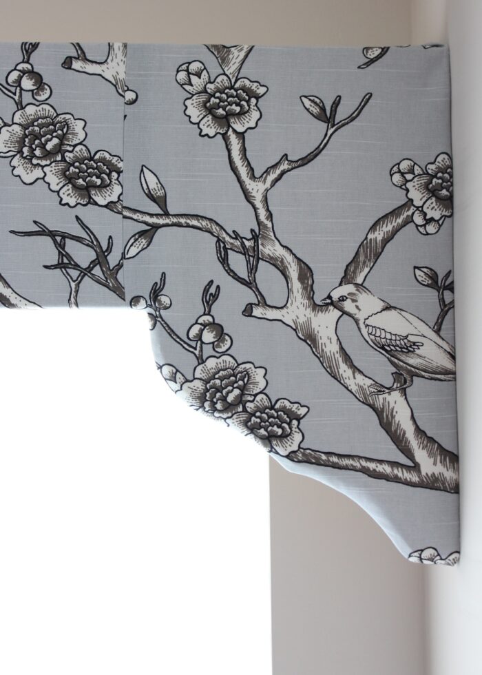 Curved window valance covered in grey branch fabric