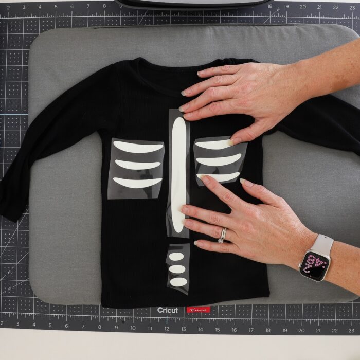 Hands placing skeleton rib bones onto a black shirt