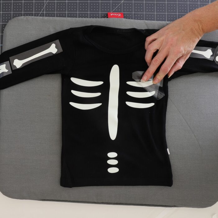 Hand removing clear carrier sheet off skeleton bone decal on black shirt