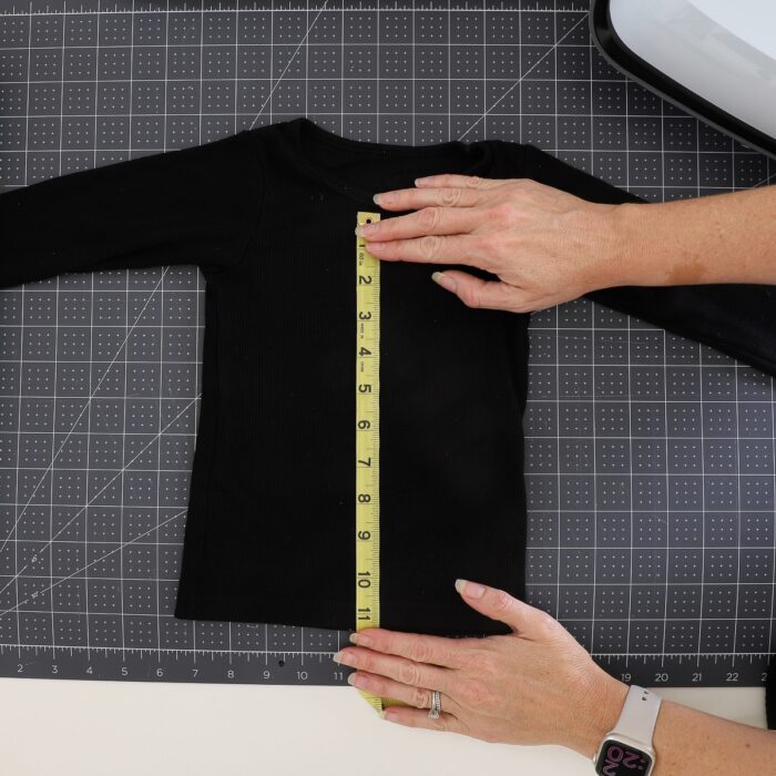Hands using measuring tape on a black shirt