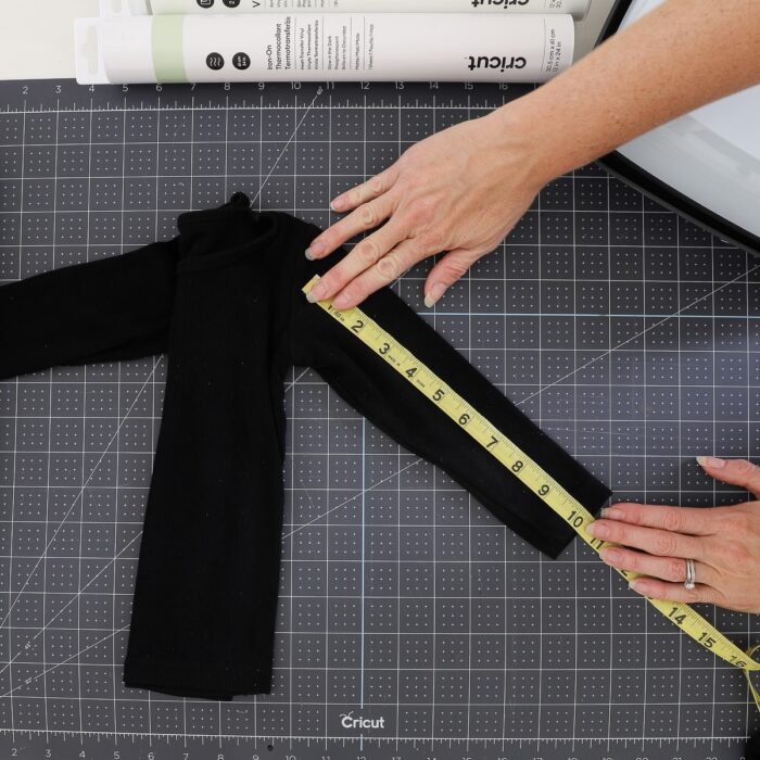 Hands using measuring tape on a black sleeve