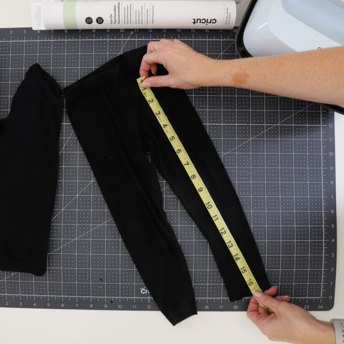 Hands using measuring tape on a black pant leg