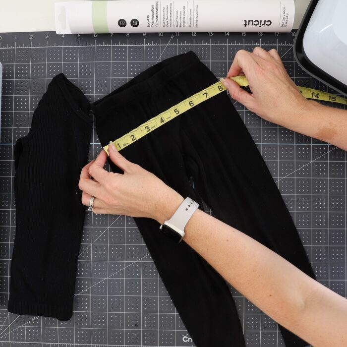 Hands using measuring tape on a black pants