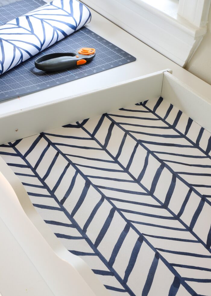 White drawer lined with blue and white contact paper shown next to cutting mat and rotary cutter