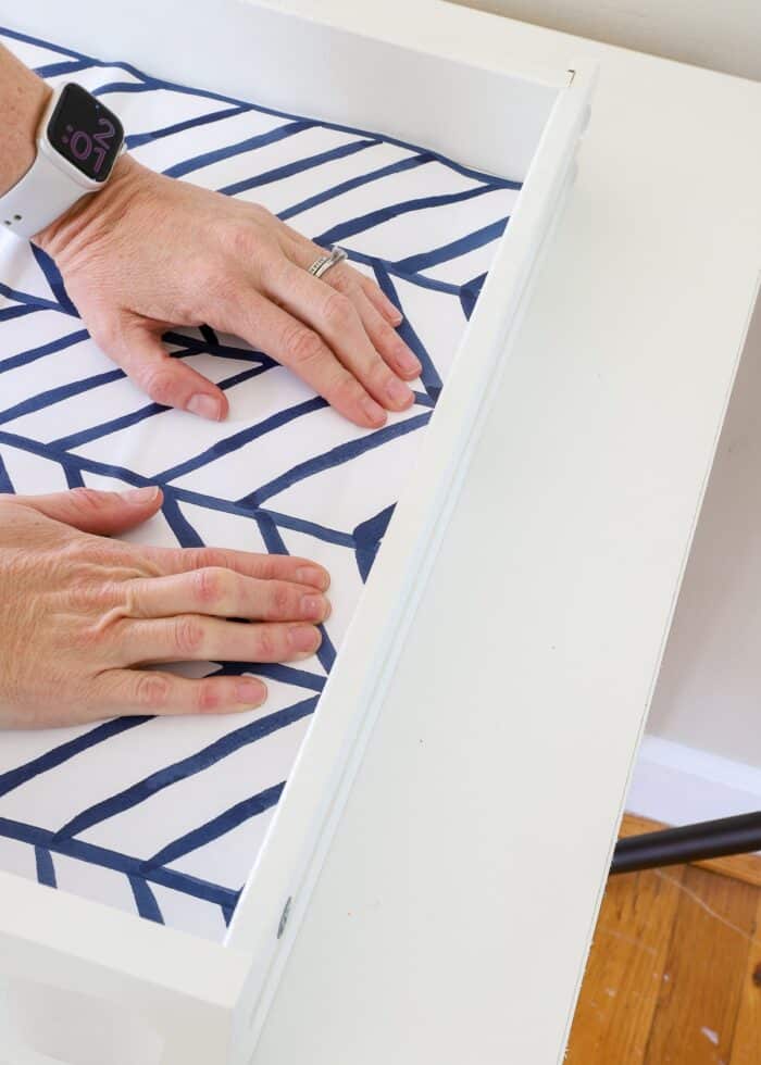 Hands smoothing down contact paper inside a drawer