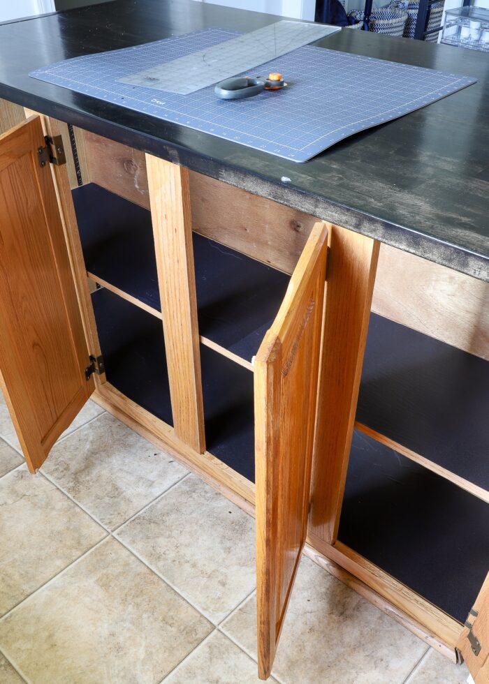 Lower kitchen cabinets with doors open showing black shelf liner on shelves