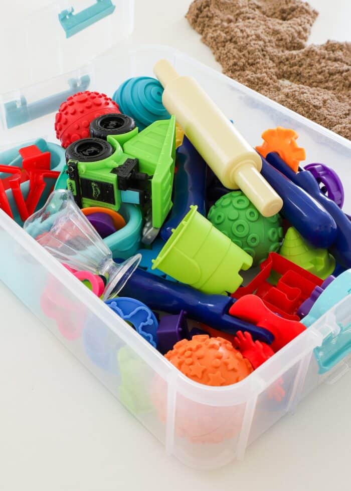 Kinetic sand toys and tools loaded into a snap-lid caddy