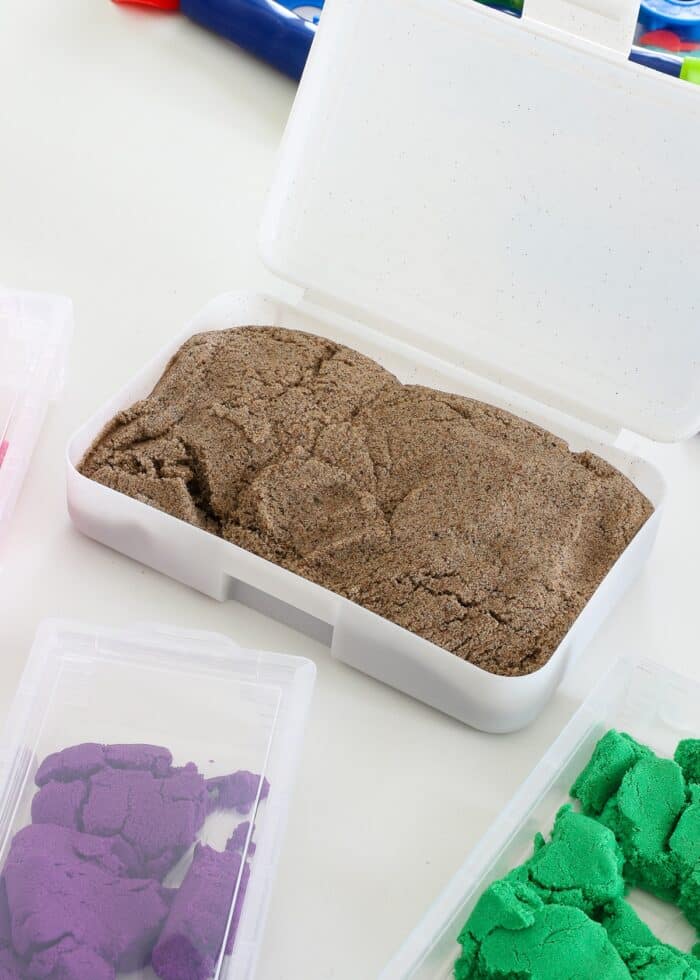 Brown kinetic sand loaded into a clear pencil box