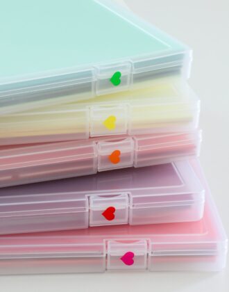 Clear craft paper storage boxes labeled with rainbow vinyl hearts
