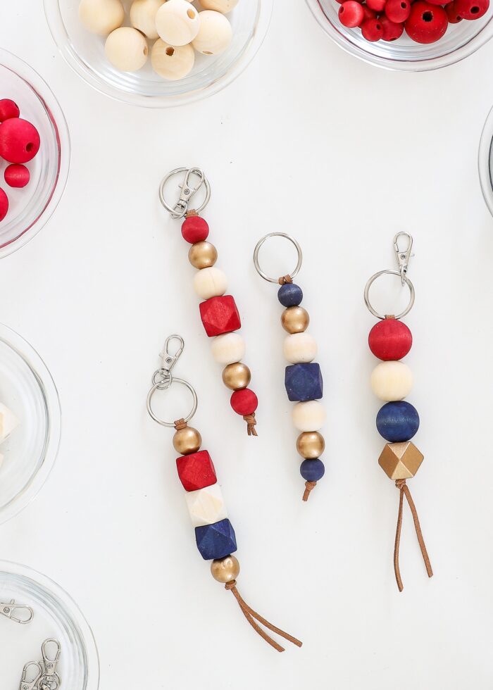 Red, white, blue, and gold wood bead keychains on a white table