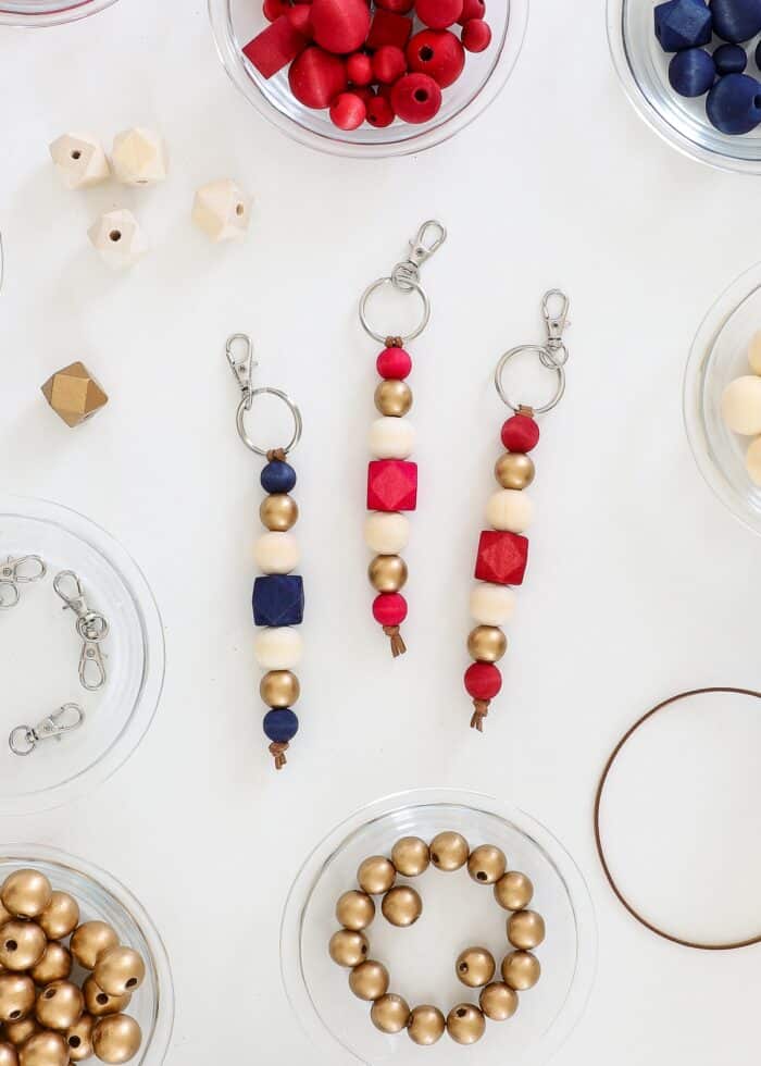 Red, white, blue, and gold wood bead keychains on a white table