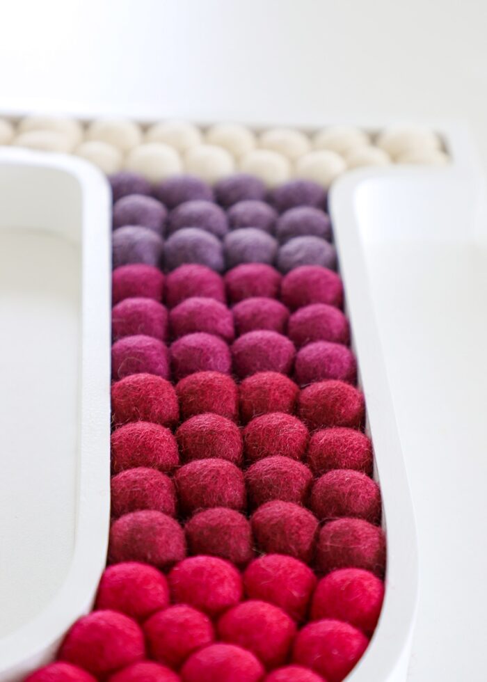 Pom Pom Letter J Wall Art made with shades of red felt balls