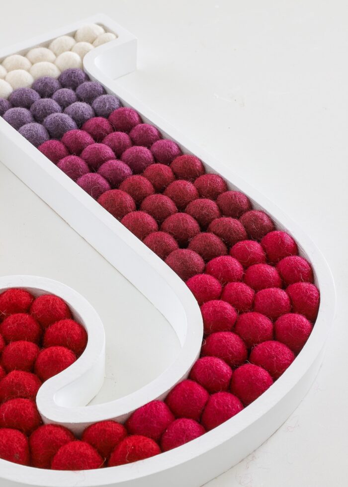 Pom Pom Letter J Wall Art made with shades of red felt balls