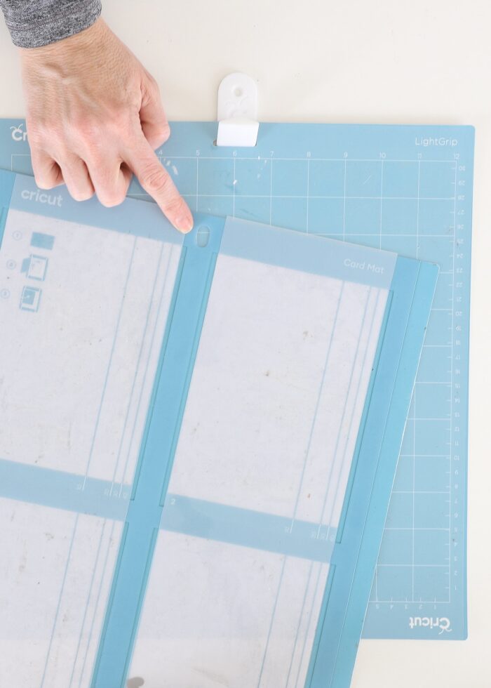 Hand pointing to round hole on Cricut Card Mat