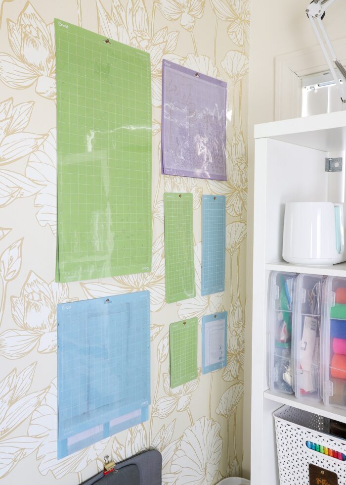 Corner of a craft room with Cricut cutting mats organized and hung on the wall.