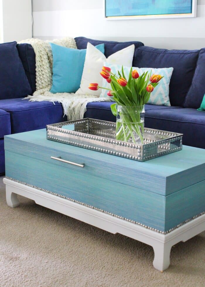 Trunk coffee table covered in turquoise grasscloth wallpaper