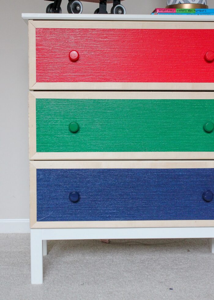 Dresser with red, blue, and green paintable wallpaper on drawers