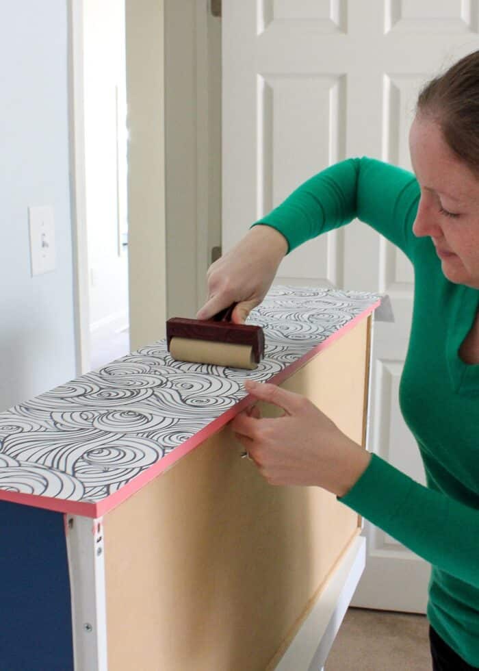 Megan adhering wallpaper to painted drawer