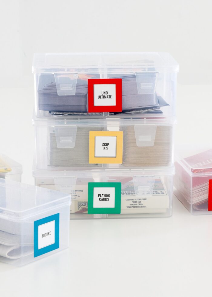Plastic playing card storage boxes labeled with colored square stickers