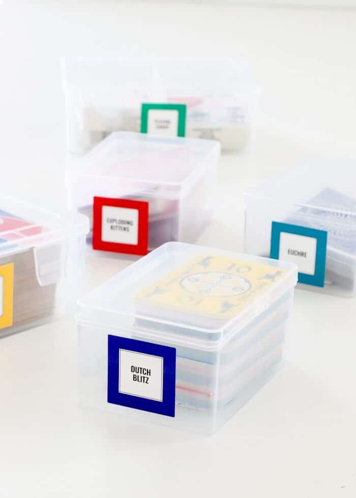 Plastic playing card storage boxes labeled with colored square stickers