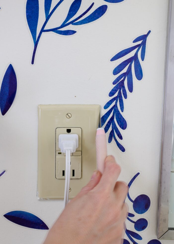 Hand using craft knife to trim down bathroom wall decals
